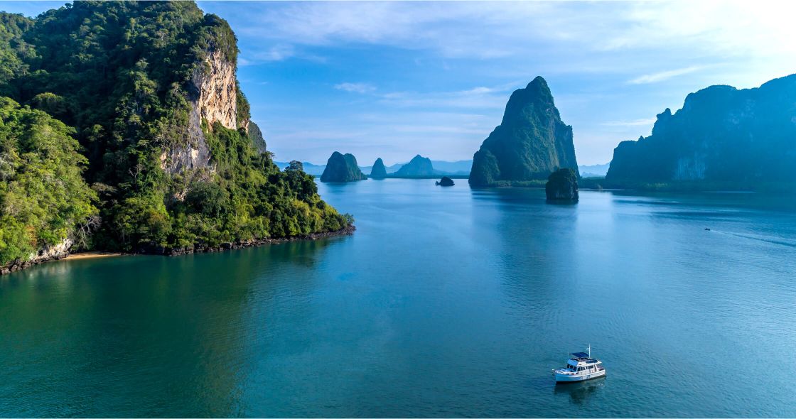 A Boat On A Lake Surrounded By Trees And Mountains
