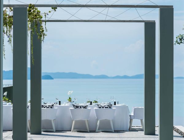 A Patio With Tables And Chairs Overlooking The Ocean