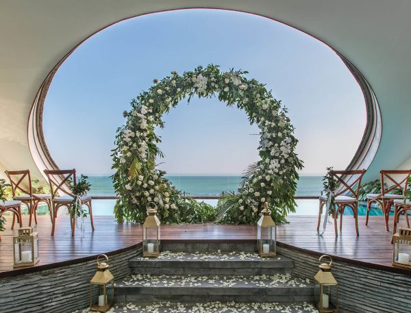 A Patio With Tables And Chairs And A Large Arch Over The Water