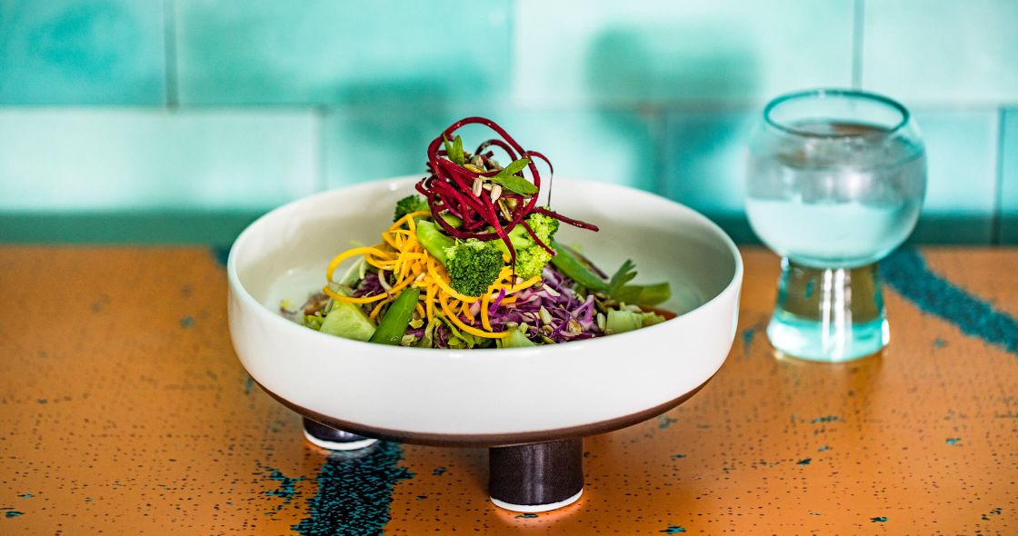 A Bowl Of Salad And A Glass Of Water On A Table
