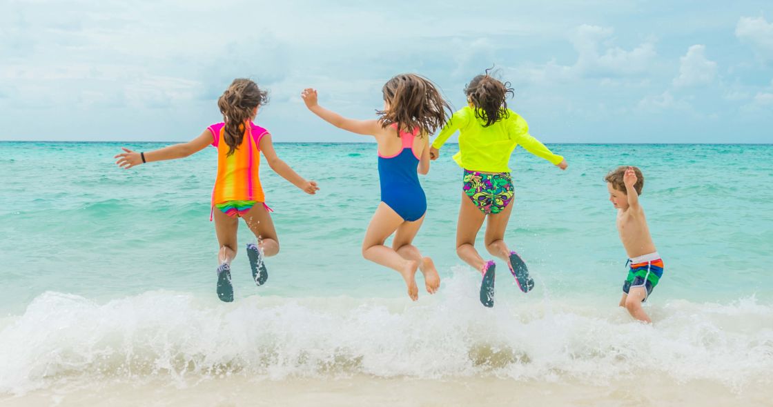 A Group Of Children Jumping In The Water