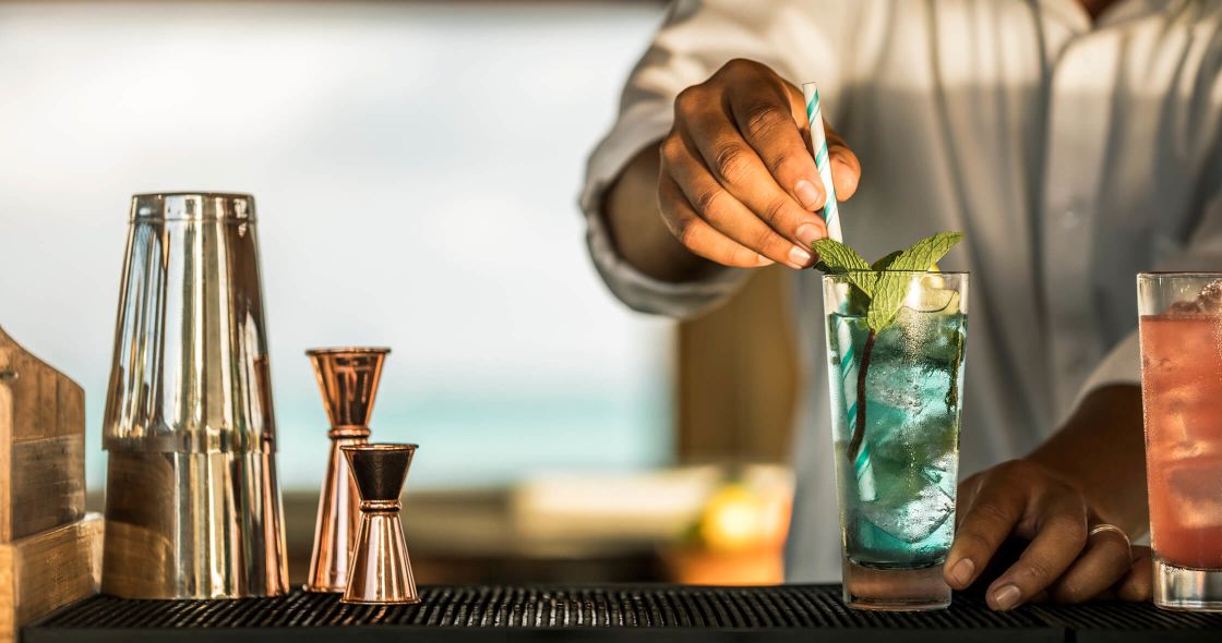 A Person Holding A Plant In A Glass With Liquid In It