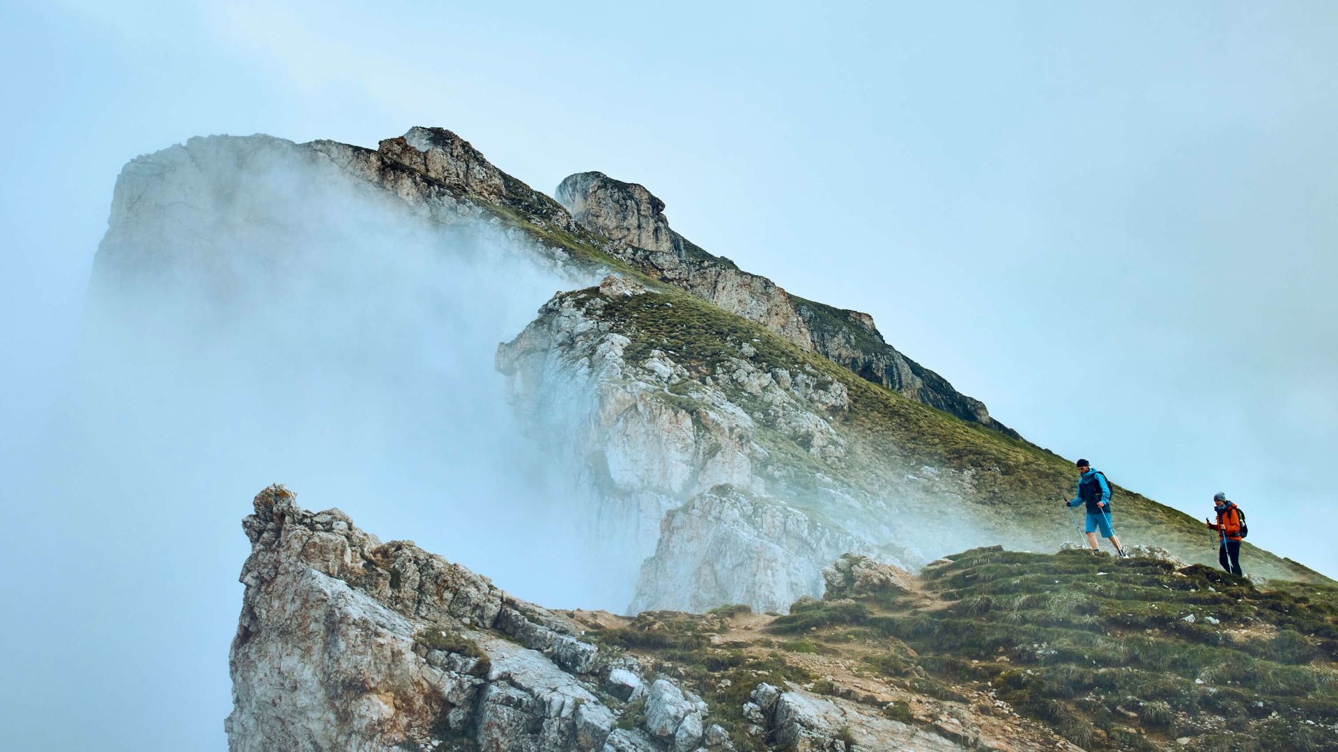 A Group Of People Standing On A Mountain Top With Clouds
