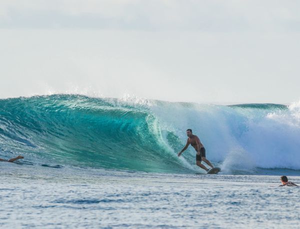 A Group Of Surfers Riding A Wave