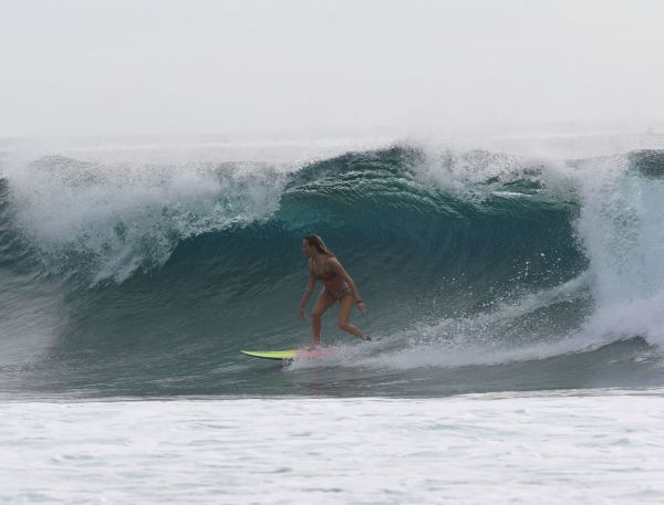 A Man Surfing A Wave With The Wedge In The Background