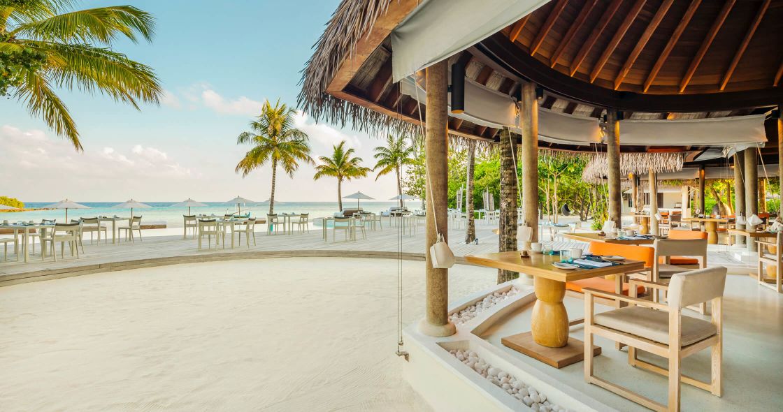 A Beach With Palm Trees And A Building