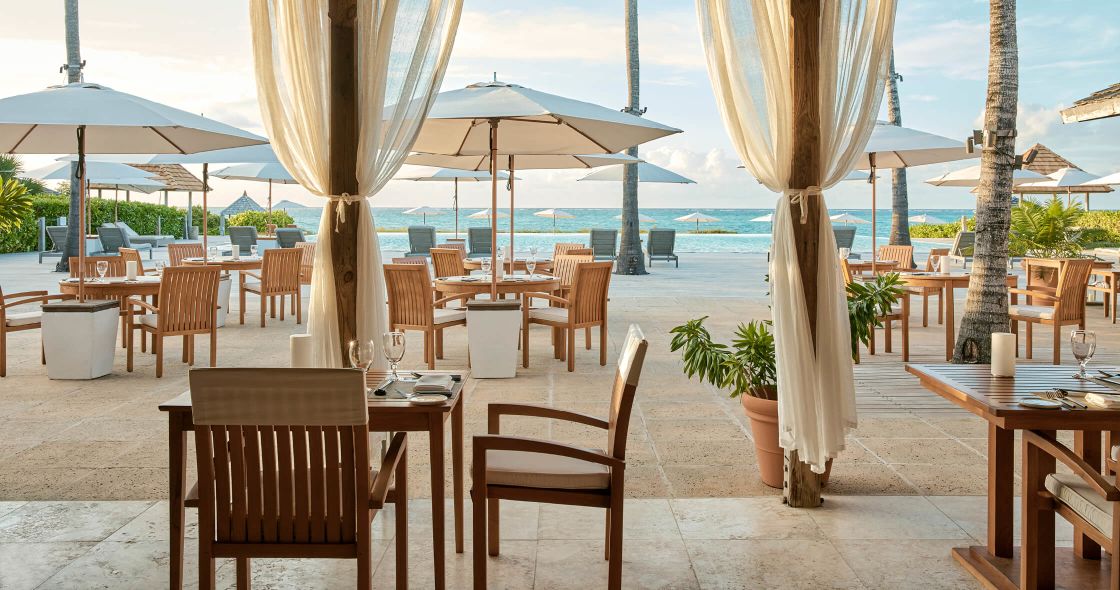 A Patio With Tables And Chairs And Umbrellas