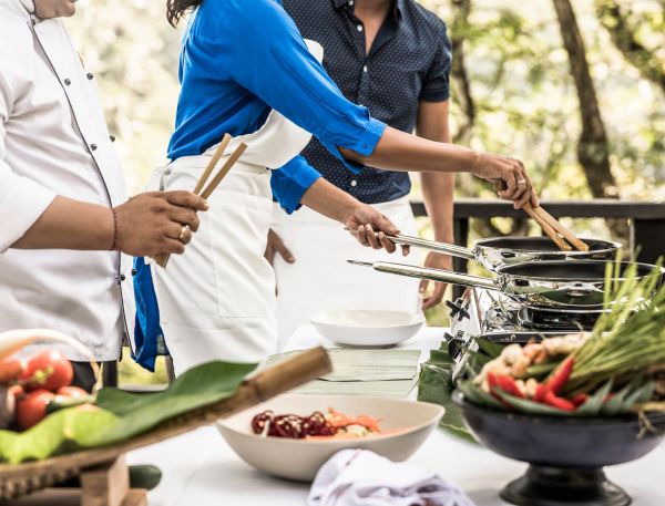 A Couple Of People Cooking Outside