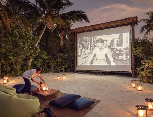 A Person Sitting On A Couch In Front Of A Large Screen
