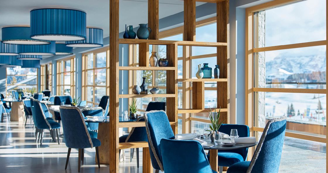 A Room With A Table Chairs And A Window With A View Of A City