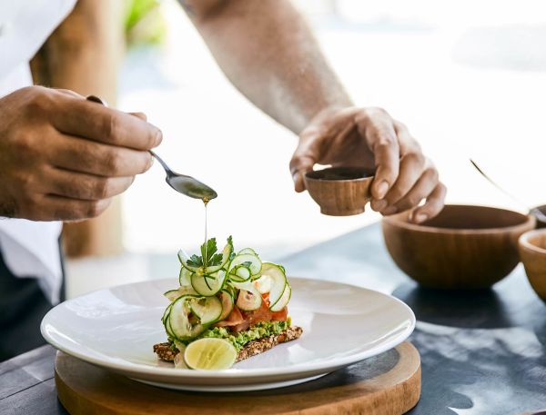 A Person Pouring A Liquid Into A Bowl Of Food