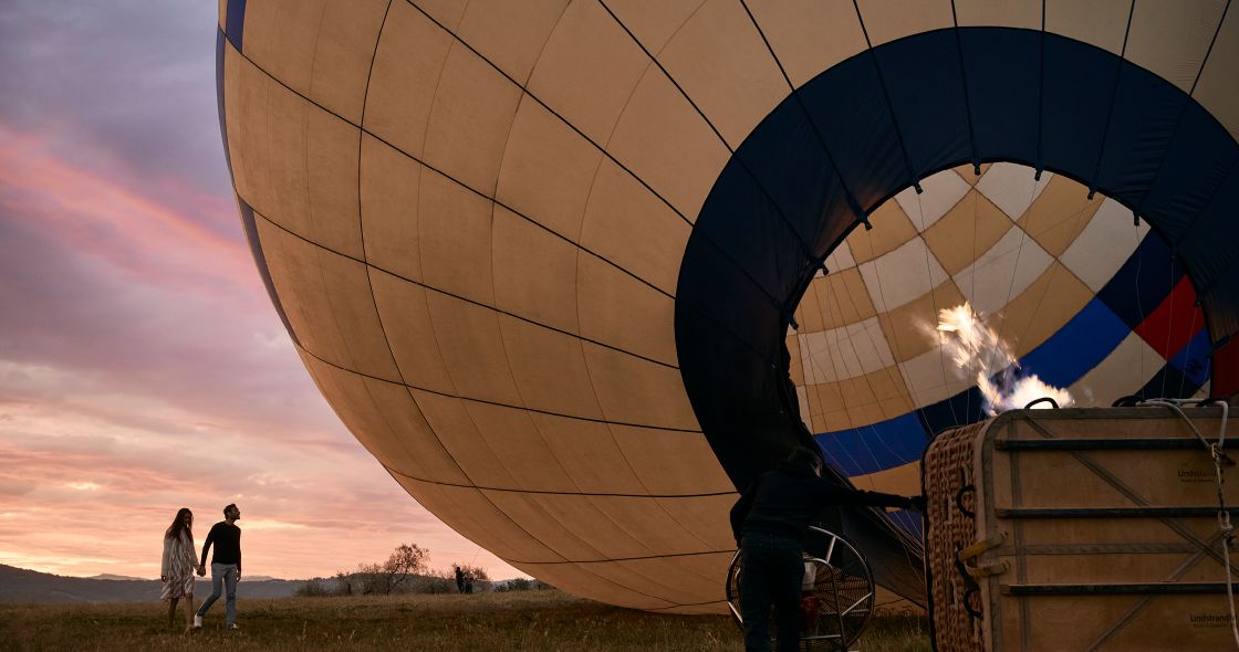 A Group Of People Standing Next To A Large Hot Air Balloon