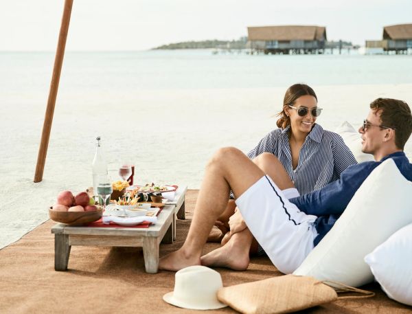 A Man And Woman Sitting On A Beach