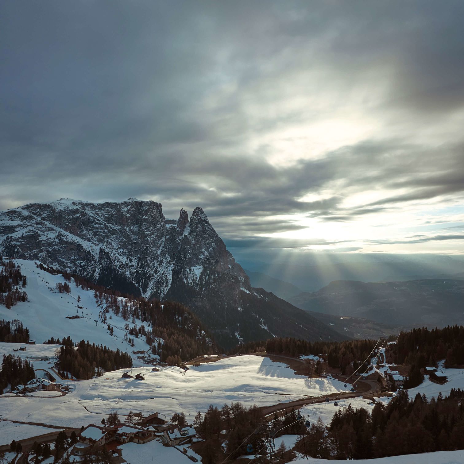 A Snowy Mountain With Trees And A Cloudy Sky