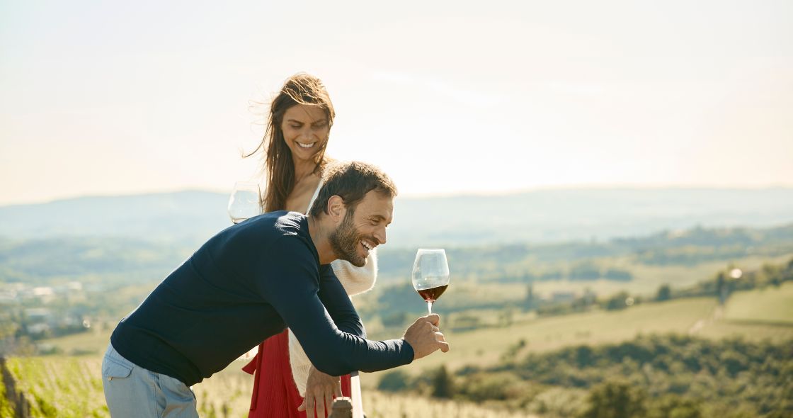 A Man And Woman Holding A Glass Of Wine