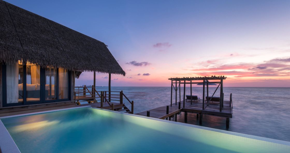A Pool Next To A Dock And A House On A Beach